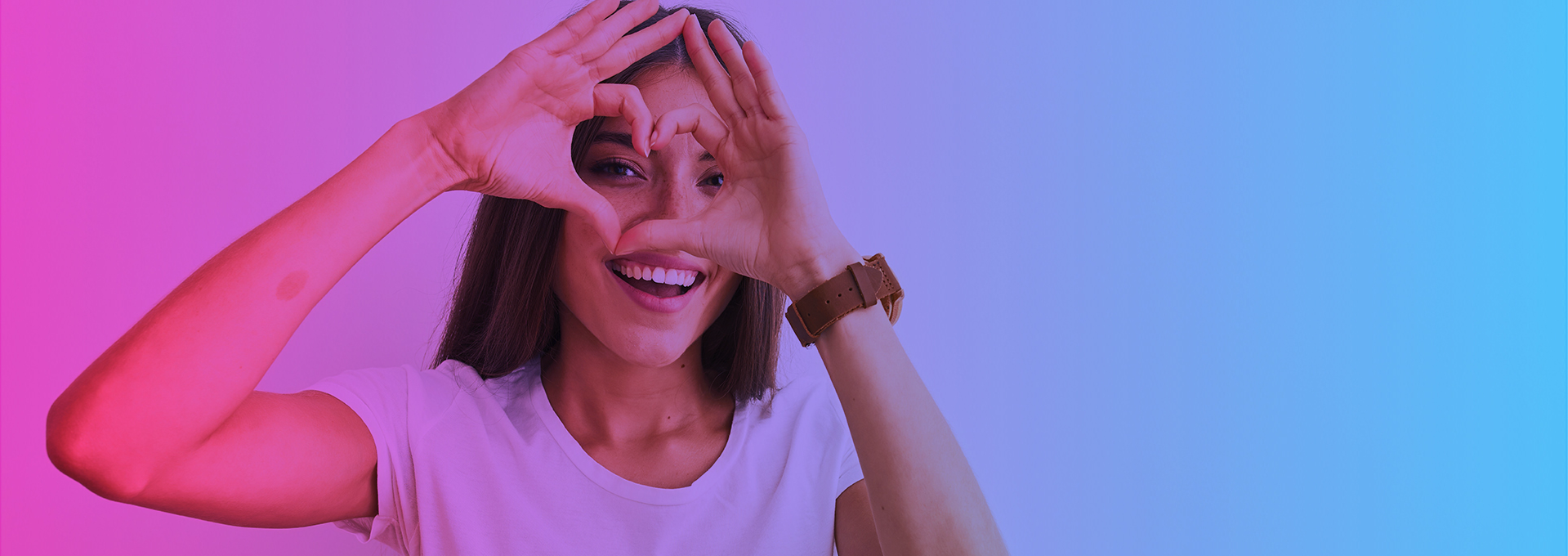 Lachende vrouw die met haar handen een hart vormt voor haar oog, op een roze-blauwe verloopachtergrond