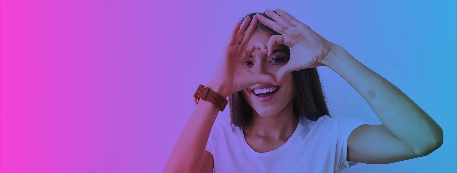 Smiling young woman making a heart shape with her hands, symbolising the emotional bond with a love brand